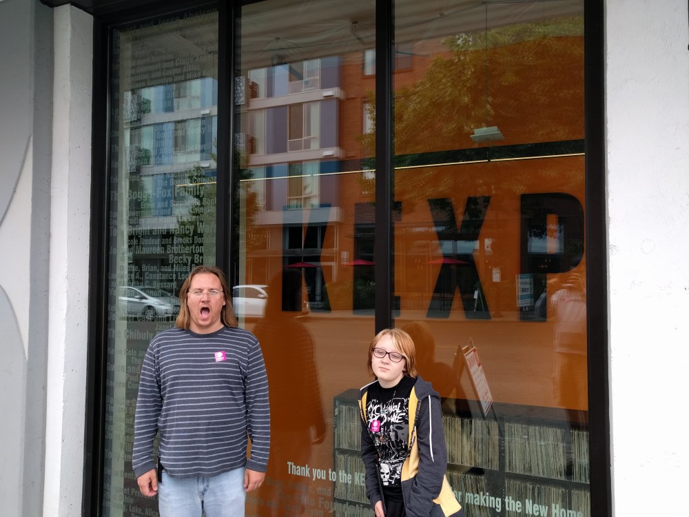 Chris Gove and his daughter, Gianna, pose in front of radio station KEXP's vinyl library.